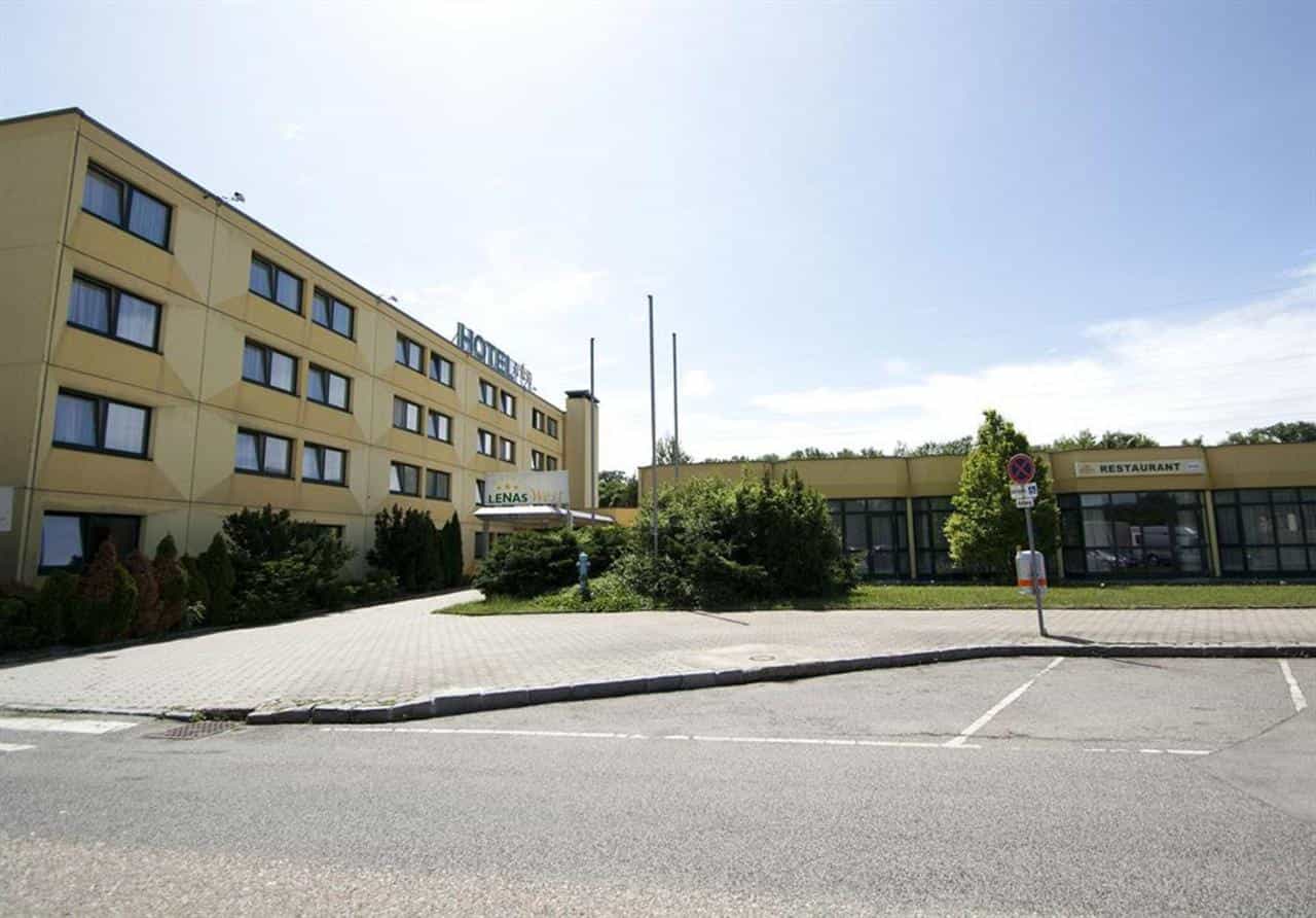 Hotel building with "Hotel" and "LENAS West" signs, adjacent restaurant, and paved lot in Vienna.