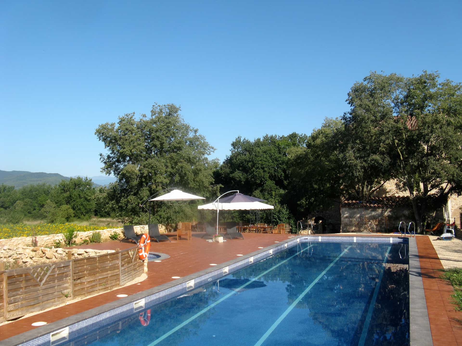 Swimming pool with lane markings on a terrace with umbrellas and lounge chairs in Girona, Spain.