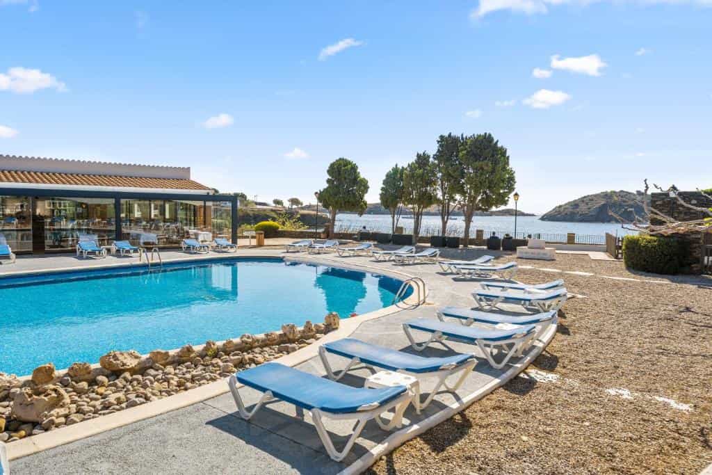Swimming pool with lounge chairs overlooking a coastal bay and trees.