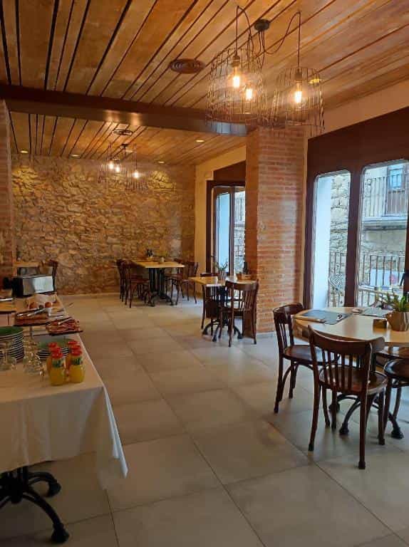 Restaurant interior with stone walls, wooden ceiling, and dining tables.