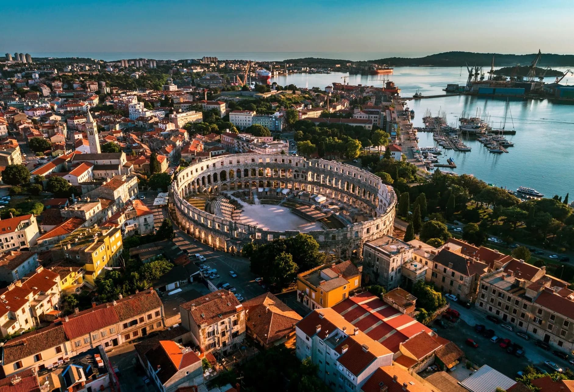 Aerial view of Pula Arena Roman amphitheater and harbor in Pula, Croatia at sunset.