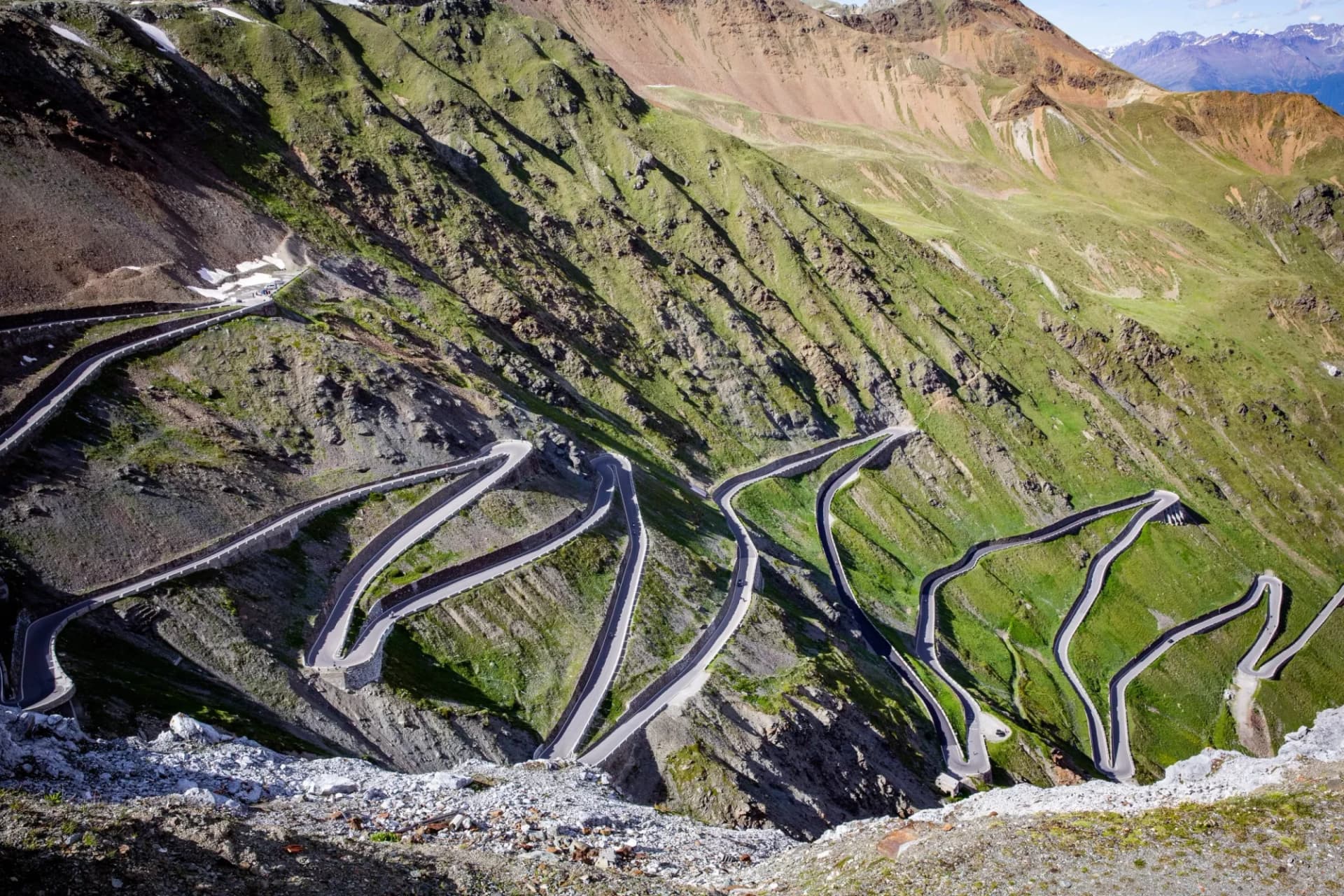 Winding mountain road with many switchbacks ascending green slopes, Stelvio Pass