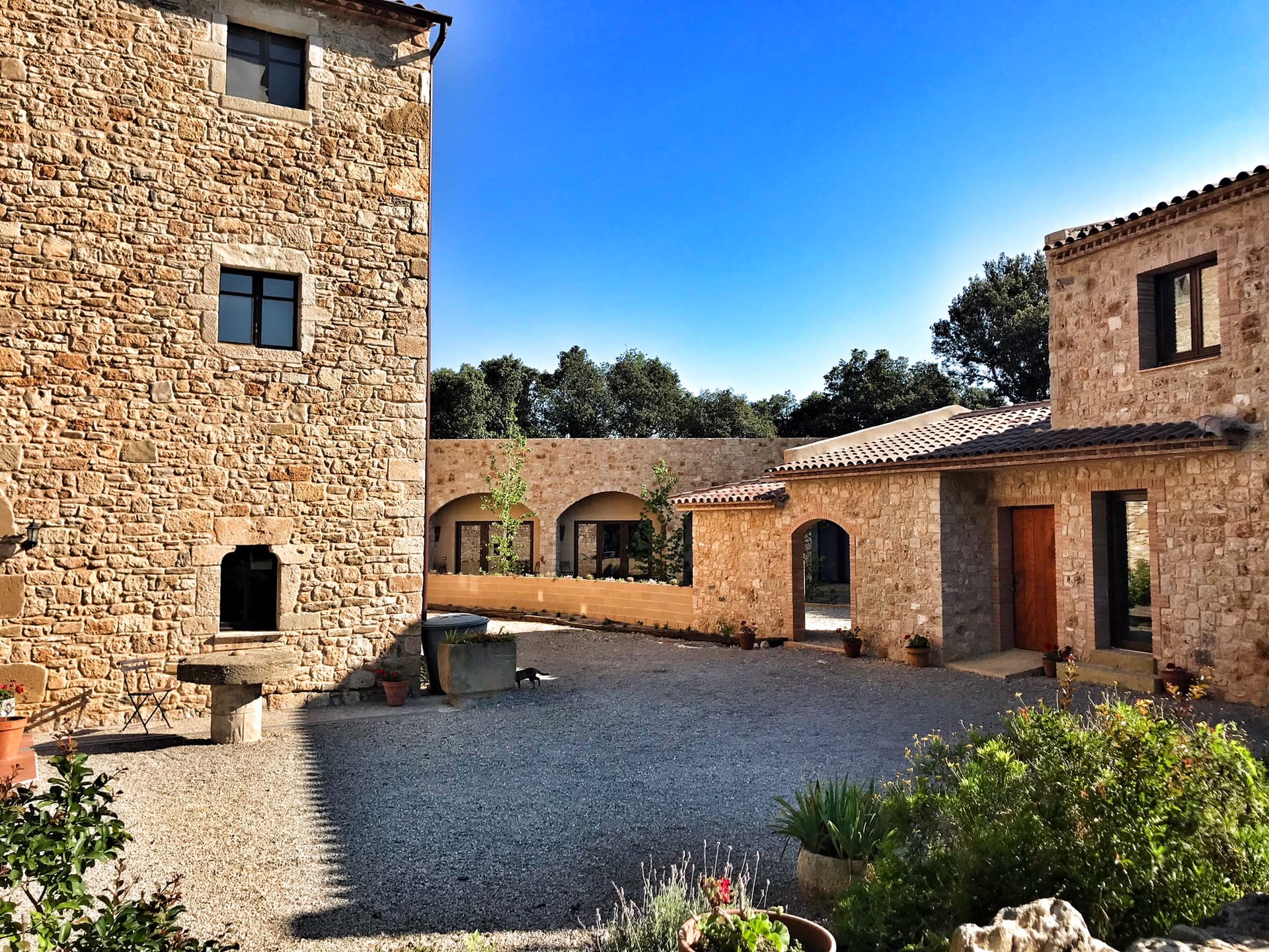 Stone buildings with arched doorways and a gravel courtyard in Girona, Spain.