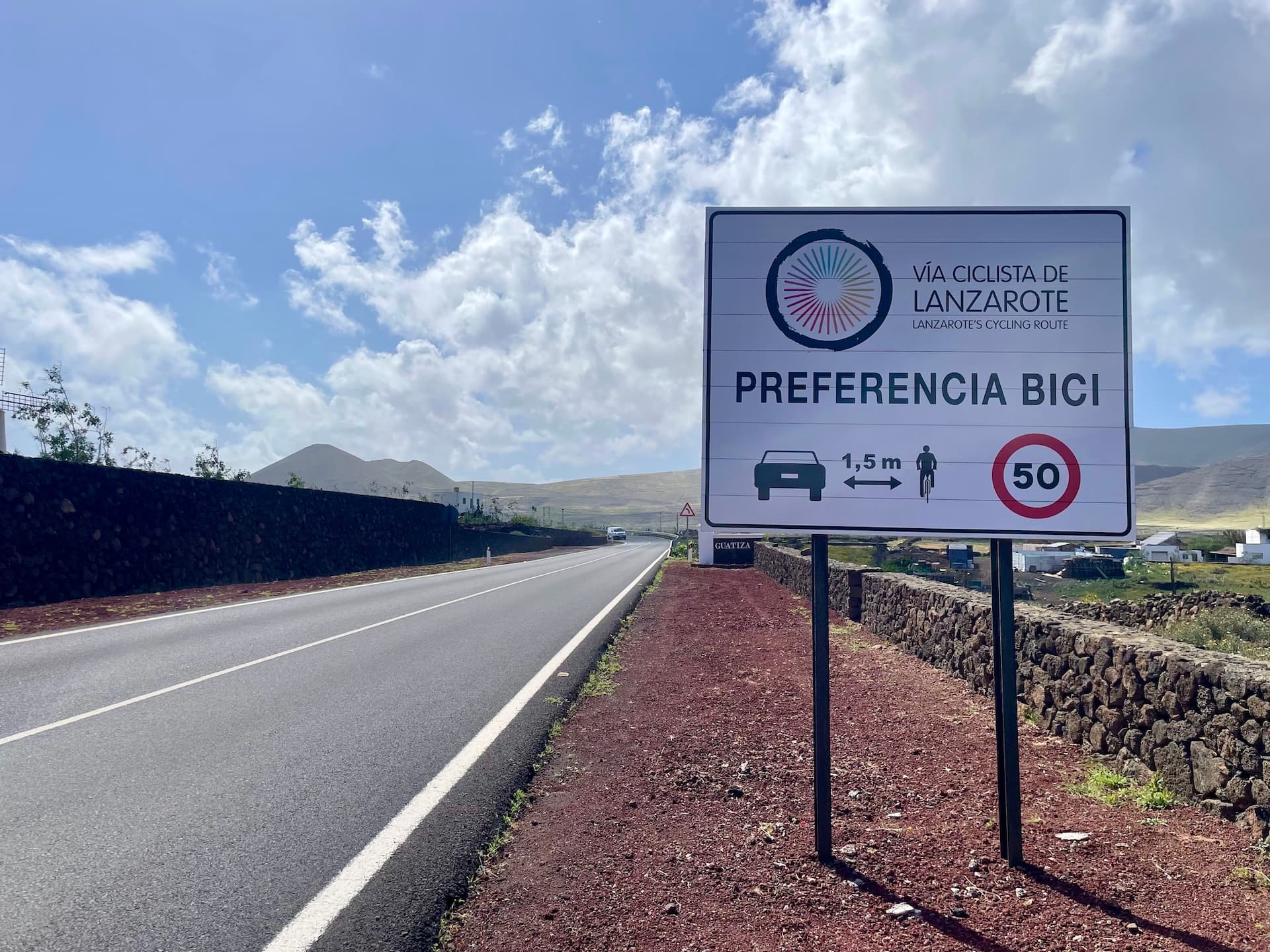 Cycling route sign on a road in Lanzarote with volcanic landscape and blue sky.