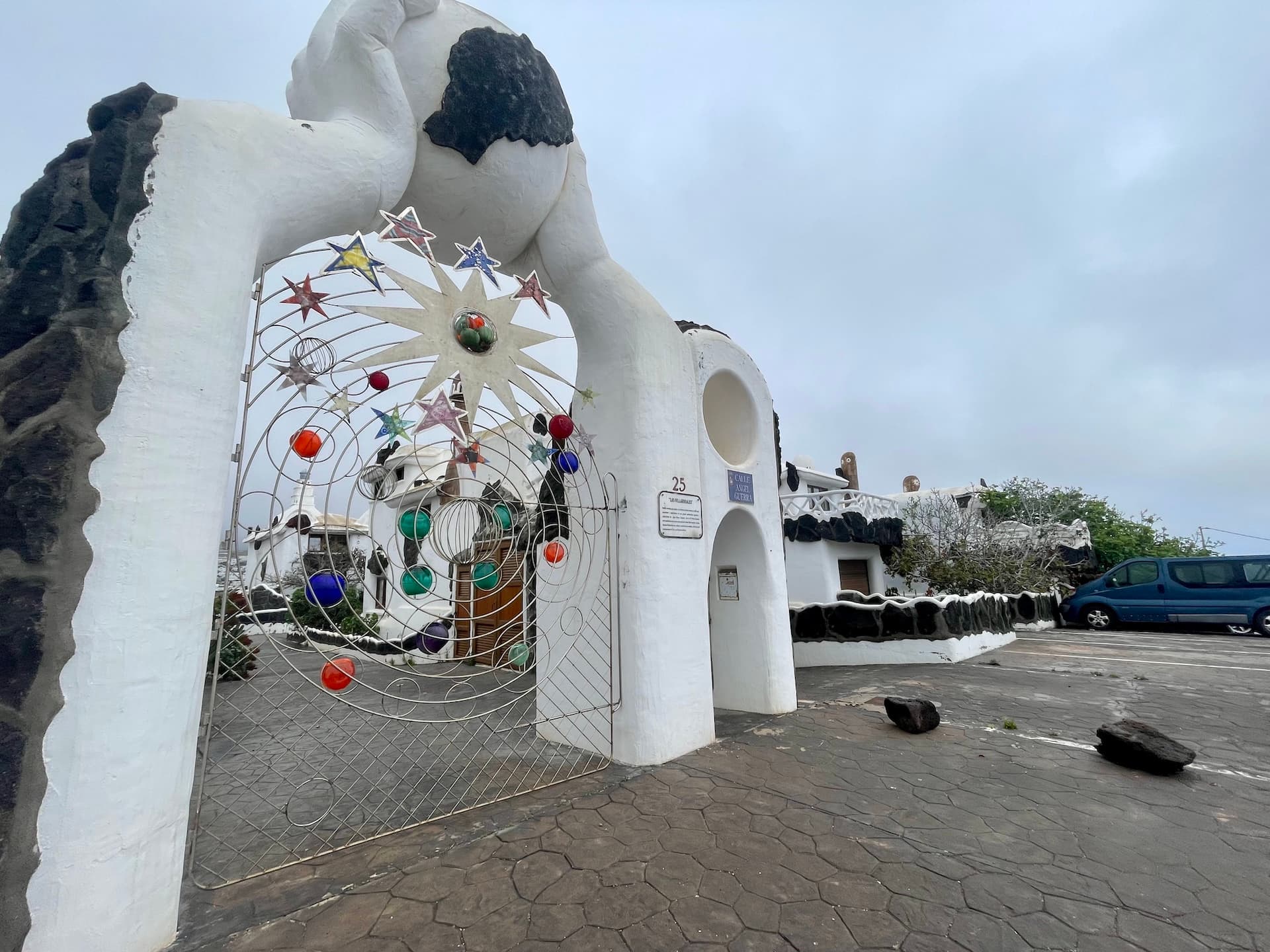 Ornate metal gate with colorful star and planet decorations at a white building entrance in Lanzarote.