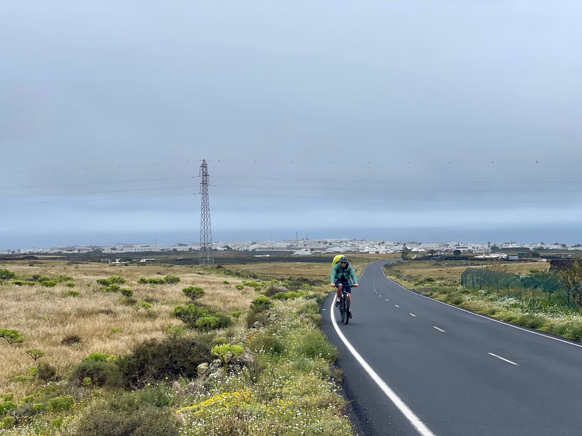 Cyclist riding on a paved road through a volcanic landscape in Lanzarote.