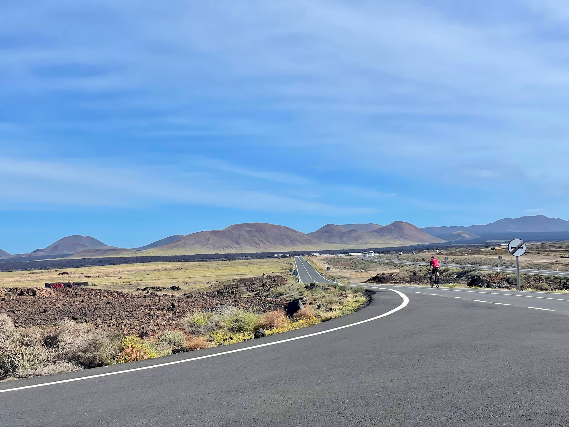 Cyclist on a road through a volcanic landscape in Lanzarote.