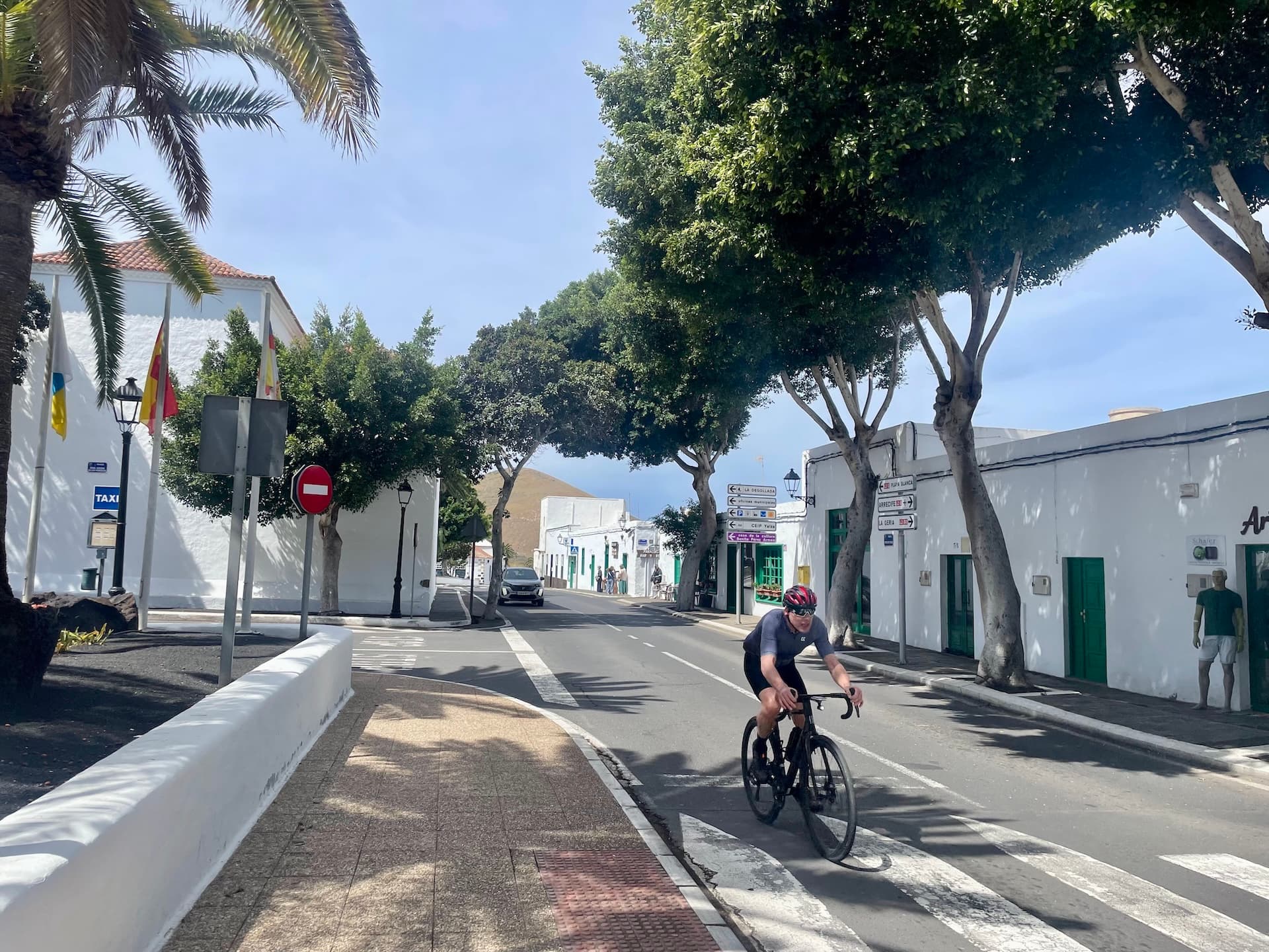 Cyclist riding on a road through a white-walled village in Lanzarote.