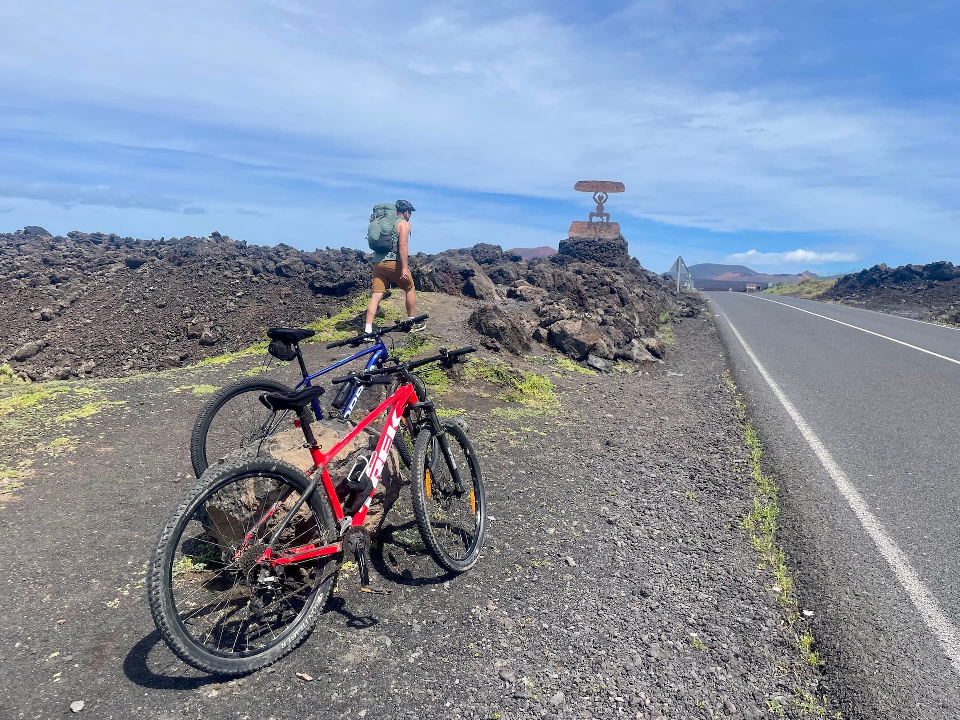 Cyclist with mountain bikes on a volcanic roadside in Lanzarote.