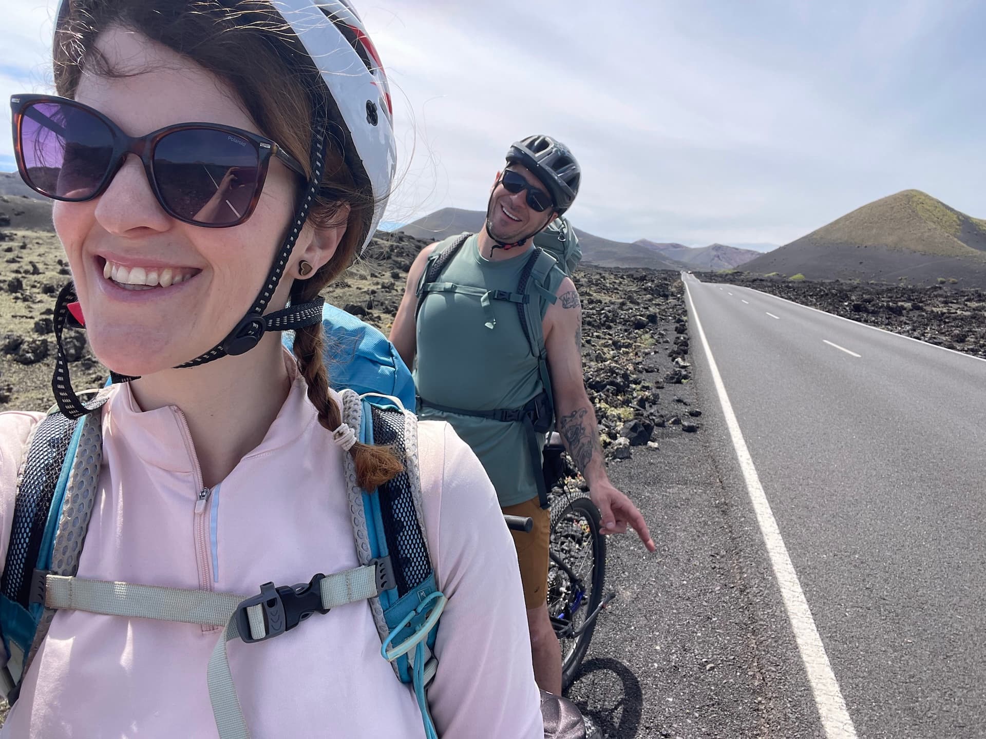 Cyclists taking a selfie on a road through a volcanic landscape in Lanzarote.