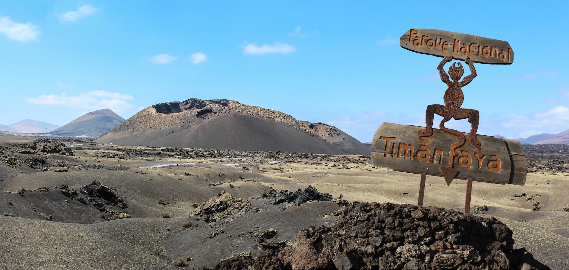 Timanfaya National Park sign with volcanic landscape and craters in Lanzarote, Canary Islands.