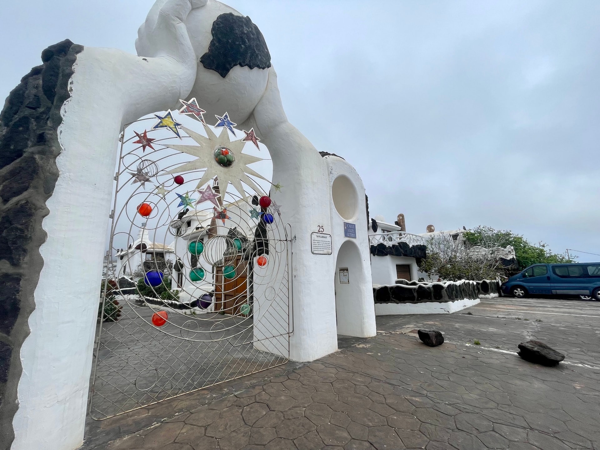 Ornate metal gate with colorful star and planet decorations at a white building entrance in Lanzarote.