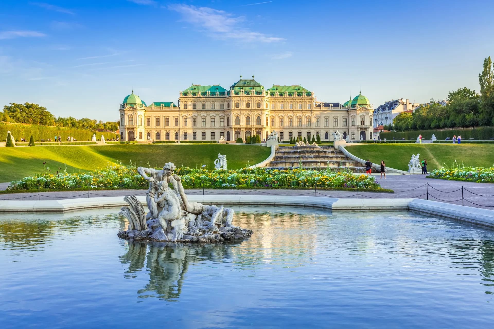Baroque palace with green roof overlooking a fountain and formal gardens in Vienna