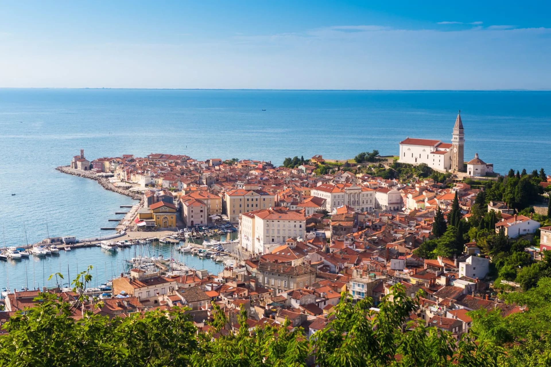 Picturesque old town Piran Slovenia with terracotta roofs, harbor, and church by the blue Adriatic Sea.