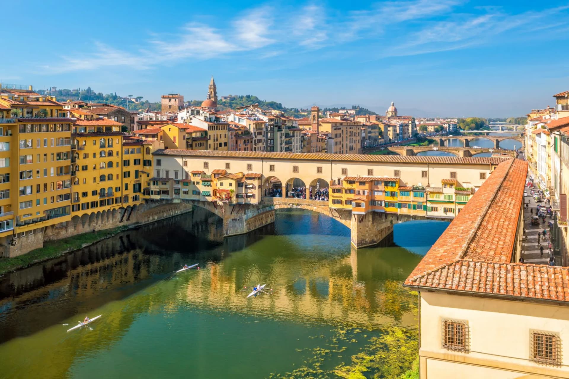 Ponte Vecchio bridge over the Arno River in Florence with rowers on the water