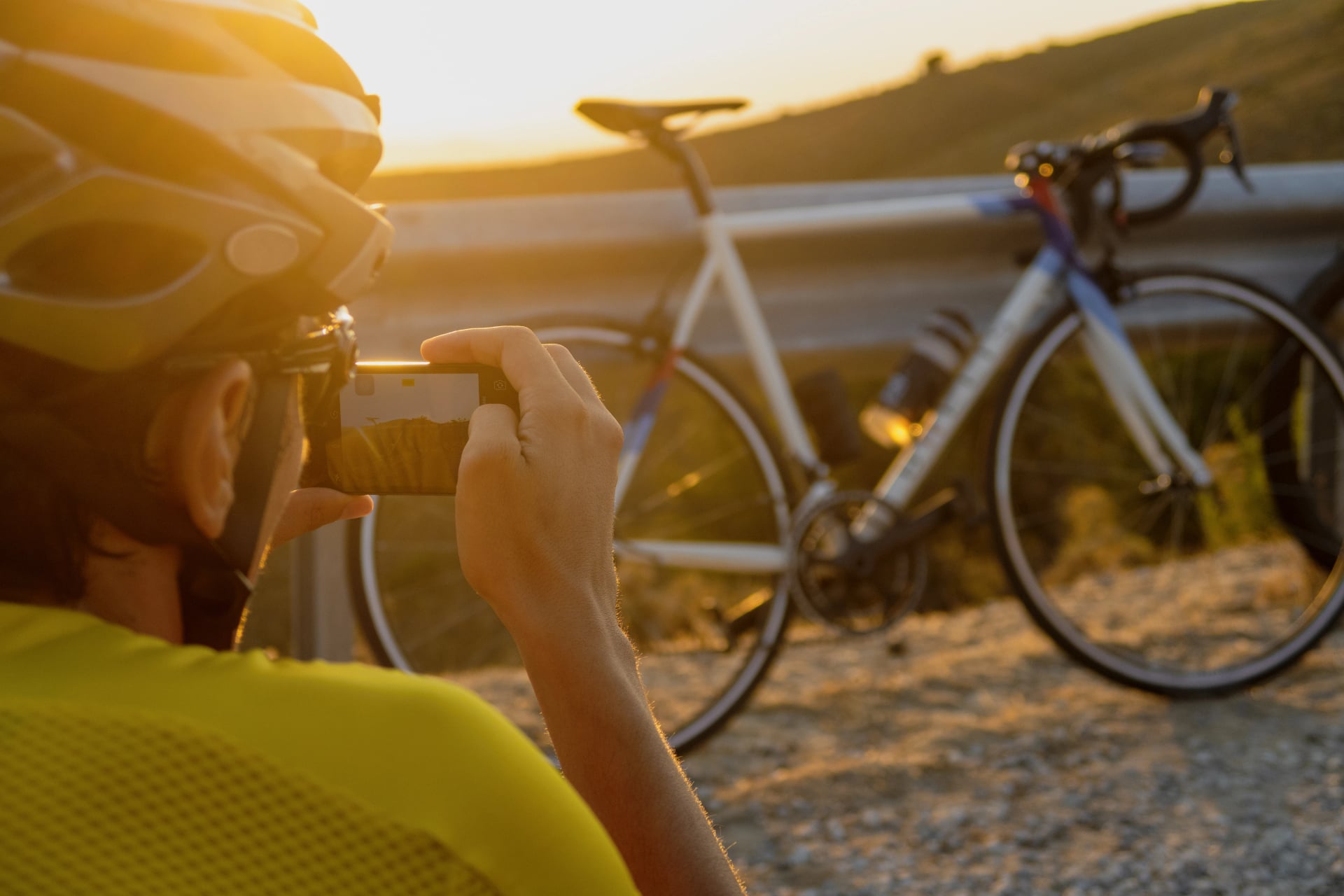 Young cyclist in a helmet taking a picture of his new bicycle on a sunny day