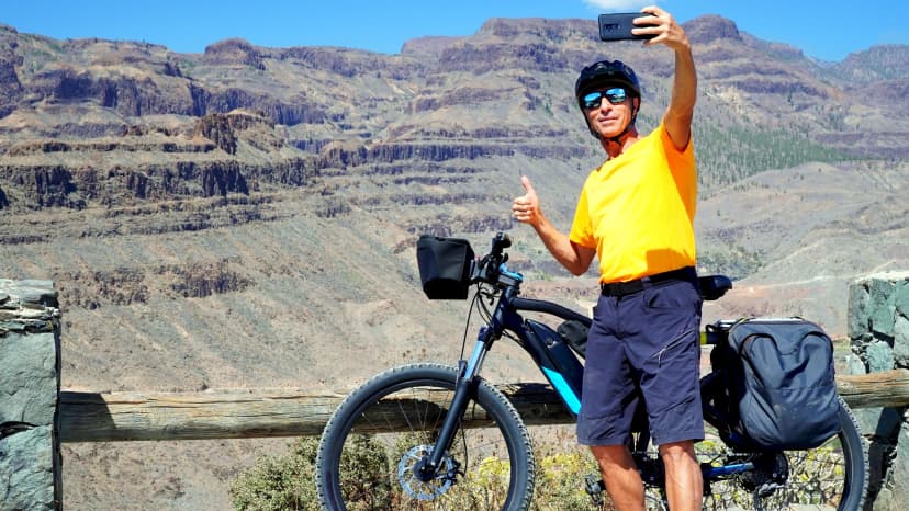 Young adult hiker cyclist taking selfie with smart phone from mountain top in Canary Islands